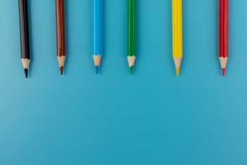 Six colored pencils close-up on a blue background with a copy of the space. The texture of bright colored wooden pencils.