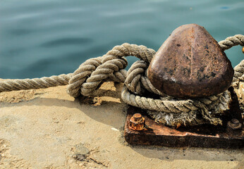 Fototapeta na wymiar Rusty mooring bollard with tied rope in the port