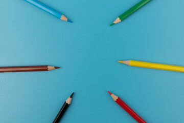 Six colored pencils close-up on a blue background with a copy of the space. The texture of bright colored wooden pencils.