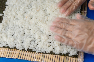 Manos preparando un rollo de Uramaki 