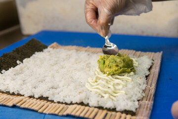 Manos preparando un rollo de Uramaki 