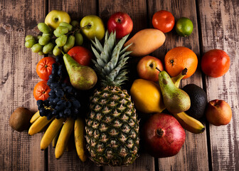 Mix of fresh juicy colorful exotic tropical fruits on wooden background top view