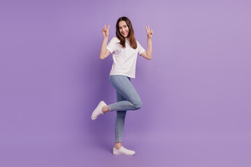 Photo of cheerful young girl raise two hands show v-sign shiny smile wear white t-shirt isolated purple color background