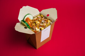Asian food to go. Opened box of rice 2 variant Indonesian seasoning, prepared in wok, mockup, red background.