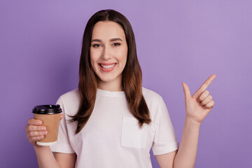 Photo of young girl enjoy cup of coffee morning indicate finger empty space ad isolated over violet color background