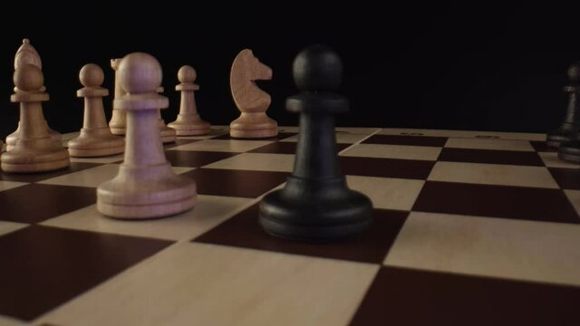 Rows of chess pieces in the dark background. Two players play against each other. The initial stage of the chess game, close-up. High quality. 4k footage.