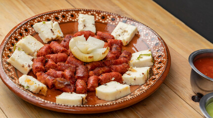 chistorra dish with cheese mounted on a clay plate accompanied by sauce. Mexican food