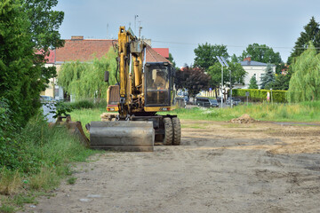 Fototapeta premium A road machine standing out of the way between the trees on a summer day. Summer.