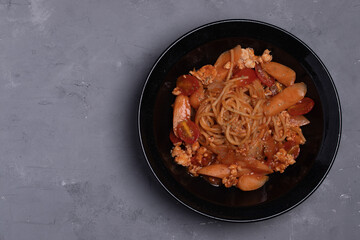 Spaghetti with tomato sauce, chicken and sausage in black plate top view. Flat lay.