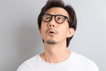 Obraz premium Asian man wearing eyeglasses with surprise and wonder expression on grey background.