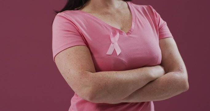 Woman with arms crossed wearing pink breast cancer awareness ribbon on t-shirt