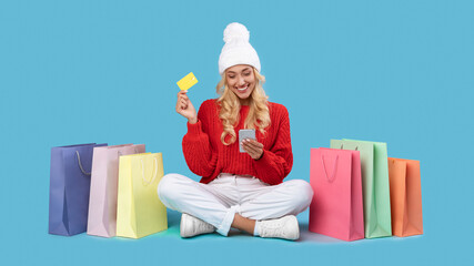 Smiling lady with shopping bags using cellphone and plastic card