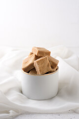 caramelized milk toffee, candy pieces in a bowl, white background