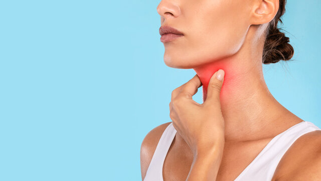 Young woman suffering from sore throat, blue studio