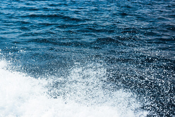 Abstract background top view blue surface ocean wave splash creating white air foam bubble on left corner leaving negative space 