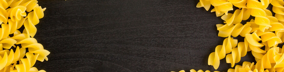 banner of Frame of A pile of pasta spiral fusilli on black background with copyspace