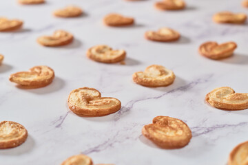 Set of Palmier puff pastry cookies or elephant ears on white marble table.
