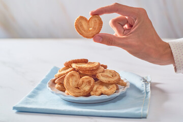 Hand holding Palmier puff pastry cookie or homemade orejitas.
