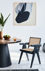 Stylish composition of dining room interior with design table, modern chairs, decoration, tropical leaf in vase, fruits, carpet, abstract mock up paintings and elegant accessories in home decor.