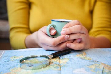 Young woman drinking coffee and planning world tour with vintage travel map - Backpacker girl looking for a new countries to explore - Journey trends, globetrotter and holiday concept - Focus on mug