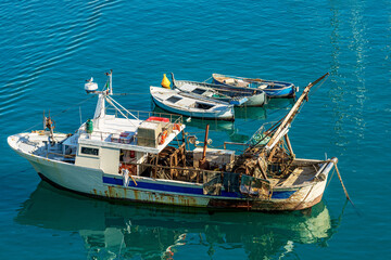 Old fishing trawler and three wooden rowing boats, moored in the Port of Lerici, tourist resort on...