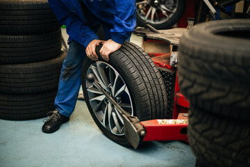 Auto mechanic balances the car wheel on the wheel balancer