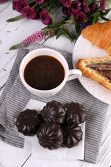 Obraz na płótnie Canvas Marshmallow in chocolate, croissant and black coffee with cinnamon on a white wooden background