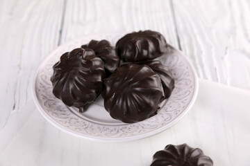 Marshmallow in chocolate on a white wooden background