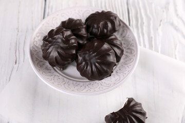 Marshmallow in chocolate on a white wooden background