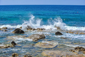 Fototapeta na wymiar The charm of the spring coast of Paphos consists of the bright color of the sea, bizarre coastal rocks and a scattering of large and small blooming plants 
