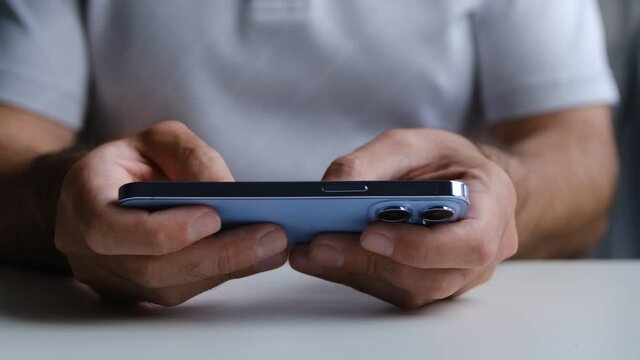 Playing mobile game on Apple Iphone 13 Pro smartphone. Man plays games on new trendy mobile phone with three cameras