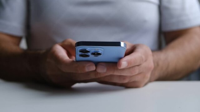 Man typing message on Apple Iphone 13 smartphone. Guy types text in messenger application on modern mobile phone device with triple camera 