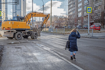 A girl crosses the roadway in the wrong place on an autumn day