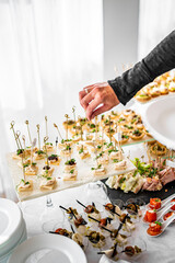 man hands take a snack and put it on plate. buffet in a restaurant