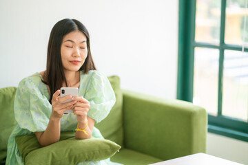 Beautiful happy women sitting on green couch use smartphone