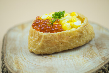 Fried tofu stuffed with rice and topping with fish roe and corn