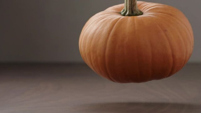 Slow motion man hand put small orange pumpkin on walnut table with copy space