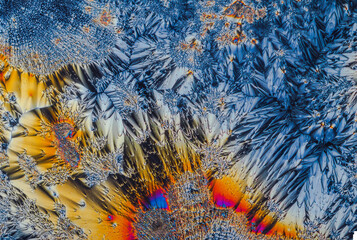 Extreme macro photograph of Vitamin C crystals forming abstract modern art patterns, when illuminated with polarized light, under a microscope objective with 10x magnification