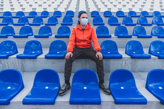 Football stands with blue plastic chairs. Football fan with a protective mask in the stadium. Sports competitions during quarantine and lockdown from coronavirus covid 19.