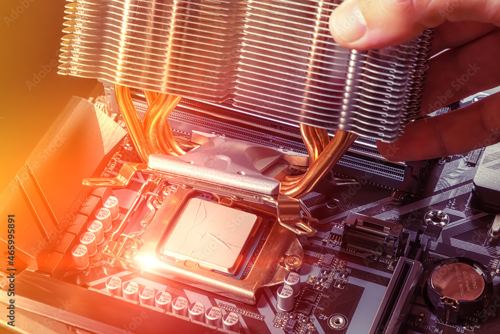 Poster installing an air cooler on a pc cpu. a technician installs an aluminum air-cooled heatsink on a des