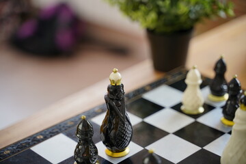 Close up of beautiful chess on table in room. Selective focus of porcelain chess pieces on chessboard.