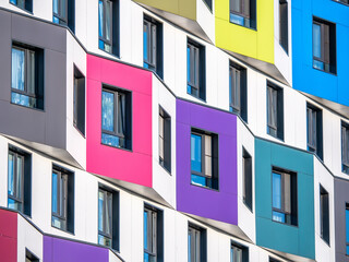 The multi-colored facade of a high-rise residential building. Rows of windows