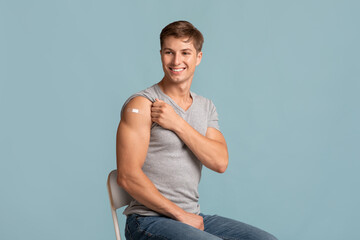 Cheerful young muscular attractive european guy showing hand with band aid after injection