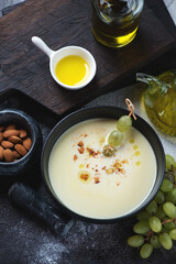 Ajoblanco or spanish white gazpacho served with grapes in a black bowl, vertical shot, elevated view