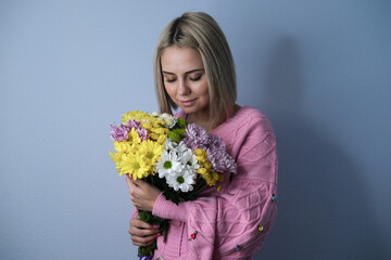 Girl holding a bouquet of flowers in her hands.Light background, close-up portrait.Concept of holiday, birthday, women's day.