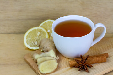 Fototapeta na wymiar Cup of tea with ginger, lemon, cinnamon sticks and star anise on rustic wooden background.