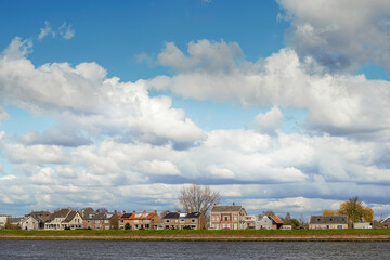 View of small houses under the blue sky with puffy clouds and the sea in the foreground