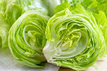 Fresh green iceberg lettuce salad leaves cut on light background on the table in the kitchen. - obrazy, fototapety, plakaty