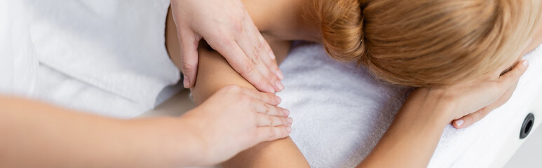 cropped view of masseur doing hand massage to blonde client, banner