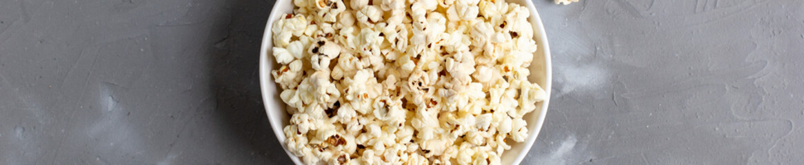 banner of Popcorn in white bowl on grey table. Top view with copyspace